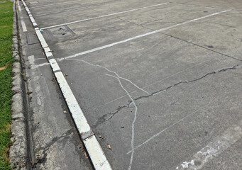 Fototapeta premium High Angle View of Empty Cracked Concrete Parking Lot Spaces with White Painted Lines and Curb