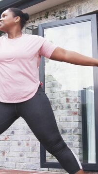 Vertical video: Flowing woman in pink top from prayer to backbend on patio with mat for fitness