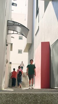 Vertical video: Walking man in green tee down alley stairs near camera bumping it onto worn panel