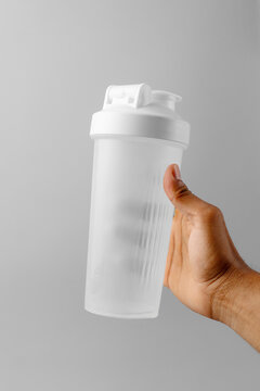Hand holding blank white shaker bottle mockup