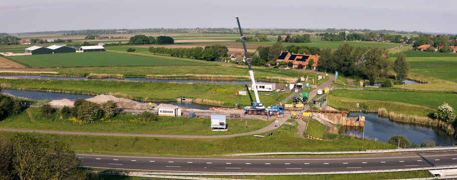 Wieringerwerf, Netherlands - 26 May 2026: Aerial view of the Stontelersluis dam reconstruction featuring a large crane and equipment surrounded by green polder landscape.