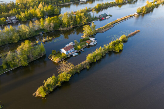 Breukelen, Netherlands - 25 April 2026: Aerial view of Scheendijk recreational islands with small cottages and boats moored along narrow strips of land in the Loosdrechtse Plassen.