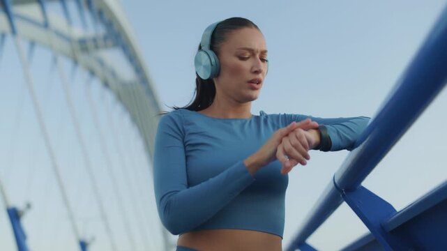 Low angle shot of female athlete checking smartwatch data during outdoor run
