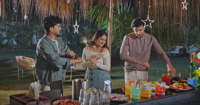 Indian young adult gen z relax male female group dancing on music sing song have fun joy at picnic trip Happy girl boy man woman standing around bar table spend good time enjoy night decor party place