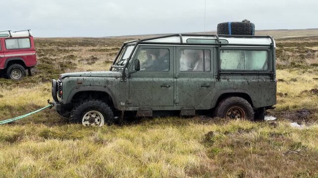 4 Wheel Drive Green Vehicle Stuck in Mud Pulled Out of Ditch. Adventure Tour Car Stalled in Hole in the Falkland Islands Rope Tow Hitch Rescued