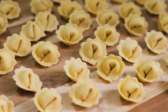 Large batch of fresh homemade cappelletti pasta on rustic wooden board, top view