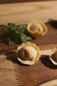 Fresh homemade cappelletti pasta with basil  on dark wood, gourmet Italian food