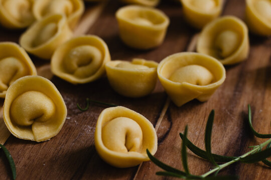 Fresh uncooked cappelletti pasta on rustic wood, low angle Italian food photography