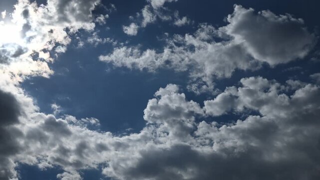 Timelapse of white and gray summer clouds moving towards the viewer the sun is in the upper left corner
