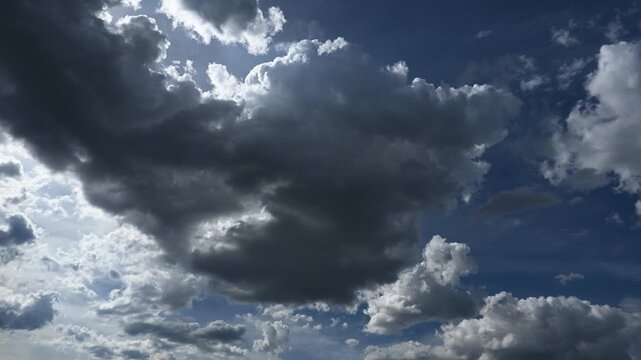 Time lapse of gray and white summer clouds moving through a blue sky with the sun in the upper left corner
