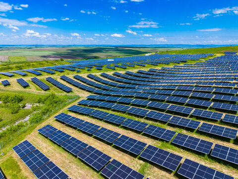 Diagonal perspective of solar rows leading toward horizon, sweeping arrangement of modules with bright reflections, conveys momentum of energy scaleup and efficiency optimization