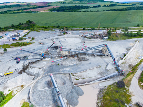 Mining complex with extensive conveyors and settling ponds visible. Expansive gravel processing facility equipped with multiple transport belts and water treatment units