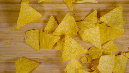 TOP DOWN: Tortilla chips fall on wooden dining table and break into tiny pieces. © helivideo