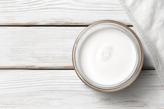 Overhead view of a glass bowl filled with white liquid on wooden surface