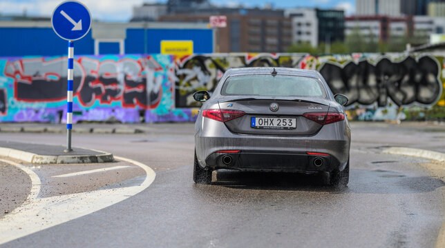 Gothenburg, Sweden - May 10 2026: 2016 Alfa Romeo Giulia driving on wet urban road.
