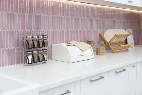 Breadbox, spices and dishware on counter in kitchen