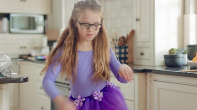 Child, home and dance with energy, freedom and creative performance with dress for music in kitchen. Girl, kid and moving to audio at house with talent for rhythm, tutu and development on weekend