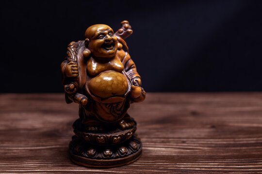 Pristine macro shot of laughing Buddha on detailed wood with clean dark background, copy-space