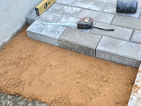Close-up of a builder installing and laying paving stones on a terrace