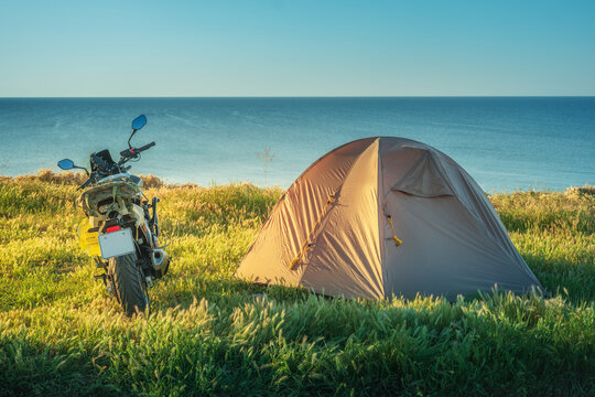 seascape with tent and motorbike on a grass meadow in morning light