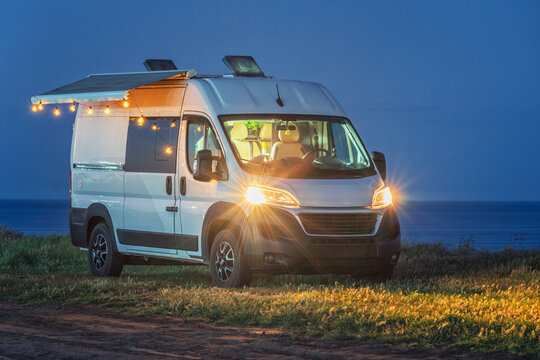 romantic lights in camper van on the cliff on sea side in evening twilight