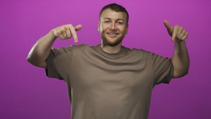 Naklejka premium Man pointing fingers down with bare hands in studio against purple backdrop; confidence promotion announcement.