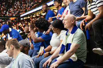 Fototapeta premium Black father spending quality weekend time with son at packed soccer stadium full of cheering fans. Football family lifestyle, parenthood and family bonding, blue team support and childhood joy.