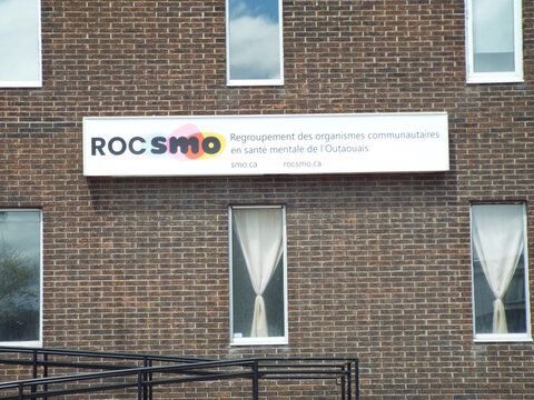 Gatineau, Quebec, Canada &ndash; May 7, 2026: A storefront sign for "ROCSMO", a mental health community organization, is mounted on a multi-story brick building facade at 92 boulevard Saint-Raymond.