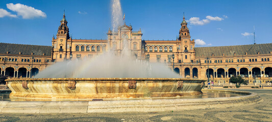 Obraz premium Wide horizontal shot of the majestic fountain with spraying water at the famous Plaza de Espana. The background features the grand renaissance-baroque style palace architecture with towers and brick a