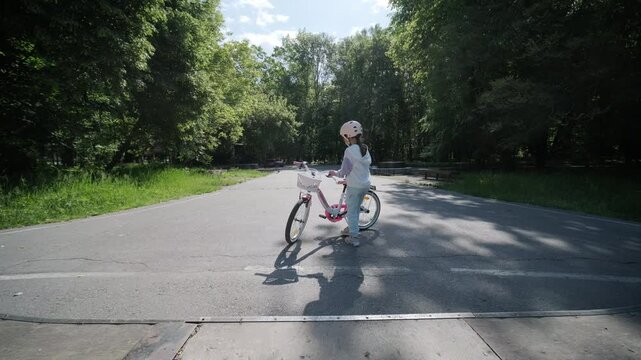 Child in a helmet posing at a public skate park in summer.