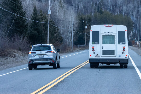 Quebec, Canada, 24 April 2026 : A silver Toyota SUV follows a white school bus displaying "Ecole Forestiere" on a rural road.