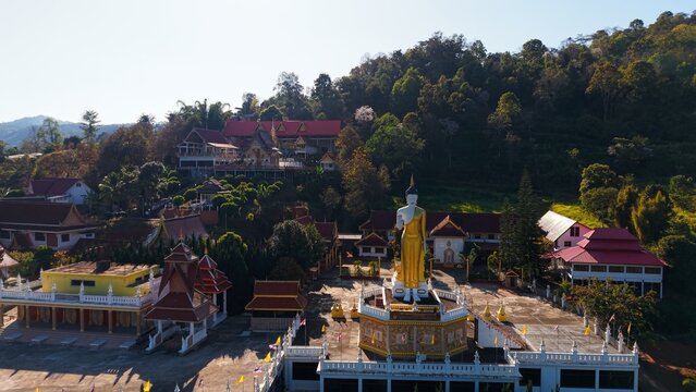 Wat pong yaeng nok temple and golden standing buddha statue on a sunny day