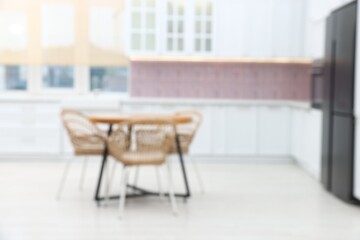 Fototapeta premium Blurred view of stylish kitchen interior with wooden table and chairs
