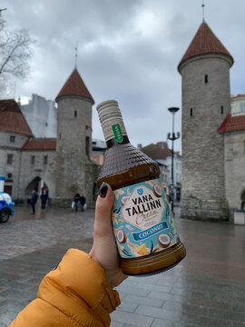 Tallinn, Estonia &ndash; February 15, 2020 &ndash; Woman holding Vana Tallinn coconut liqueur bottle with Tallinn fortress towers in background