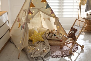 Cute wigwam with fairy lights and toys in stylish child's room © New Africa