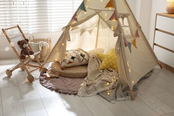 Cute wigwam with fairy lights and toys in stylish child's room © New Africa