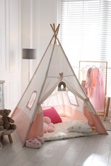 Cute wigwam, clothes, cushions and toy in stylish child's room © New Africa
