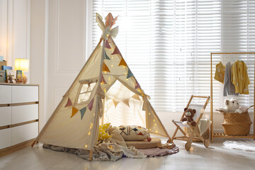 Cute wigwam with fairy lights and toys in stylish child's room © New Africa
