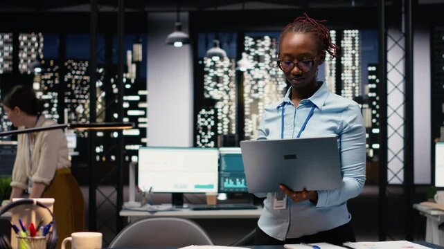 Portrait of african american woman in office managing schedules on laptop, organizing calendar appointments and meetings. Jolly young adult compiling company information records and data.