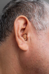 Naklejka premium Minimalist hearing aid in the ear of the middle aged man