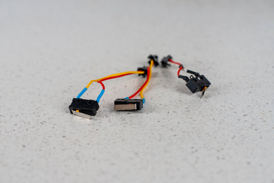 Three broken electric microswitches with damaged and cut connection wires from gas water heater on light countertop.