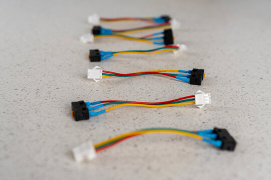 Several new electric microswitches with colored connection wires and plastic terminals for gas water heater repair on light surface.