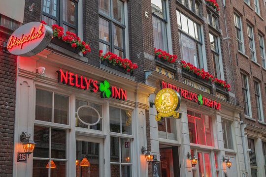 Amsterdam, Netherlands, 22.04.2026 - Historic Amsterdam street view featuring traditional brick architecture, illuminated pub signs, restaurants and nightlife venues in the city center of the Netherla