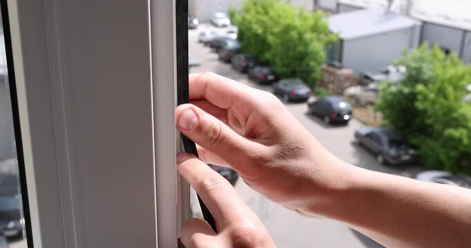 Handyman installing rubber gasket on window indoors, closeup