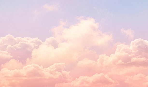 Beautiful vibrant pastel peach pink sky background with colorful fluffy soft white clouds at sunset for inspirational nature wallpaper panorama