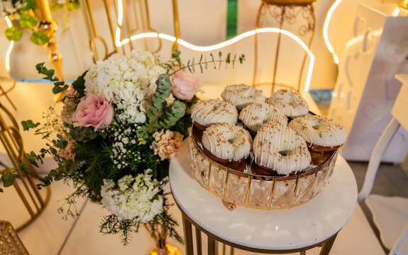 Elegante mesa de celebraci&oacute;n con donas glaseadas y arreglo floral en evento especial