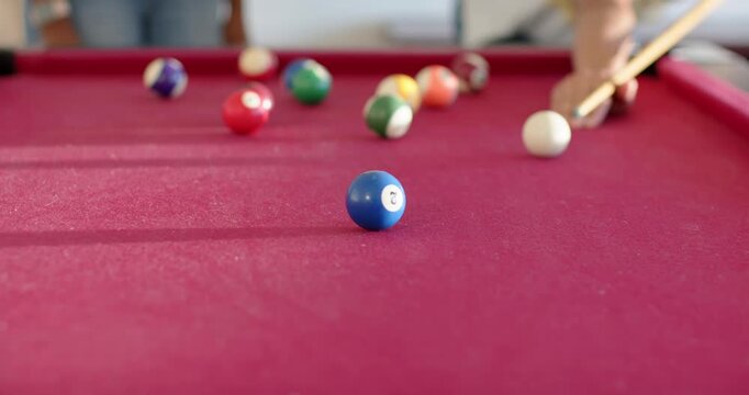 African American friends playing pool, woman hitting cue ball, sending blue 2 rolling at home table