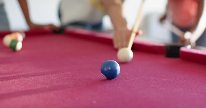 African American woman teaching teenage girl pool shots at home after cue tip striking white ball