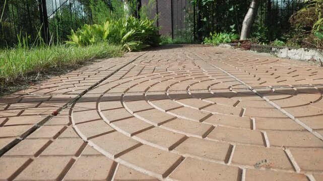 Macro closeup brick walkway in garden, meditative lowangle study of radial terracotta pavers with sunlit highlights, soft foliage shadows, subtle moss in joints, shallow depth of field and tranquil