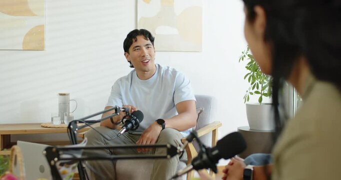 African American cohosts recording podcast in home studio, man adjusting mic and responding to host